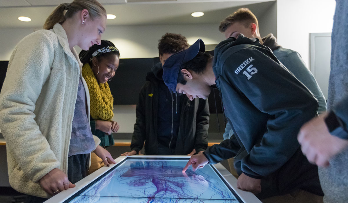 Students surrounding an anatomage table and interacting with it