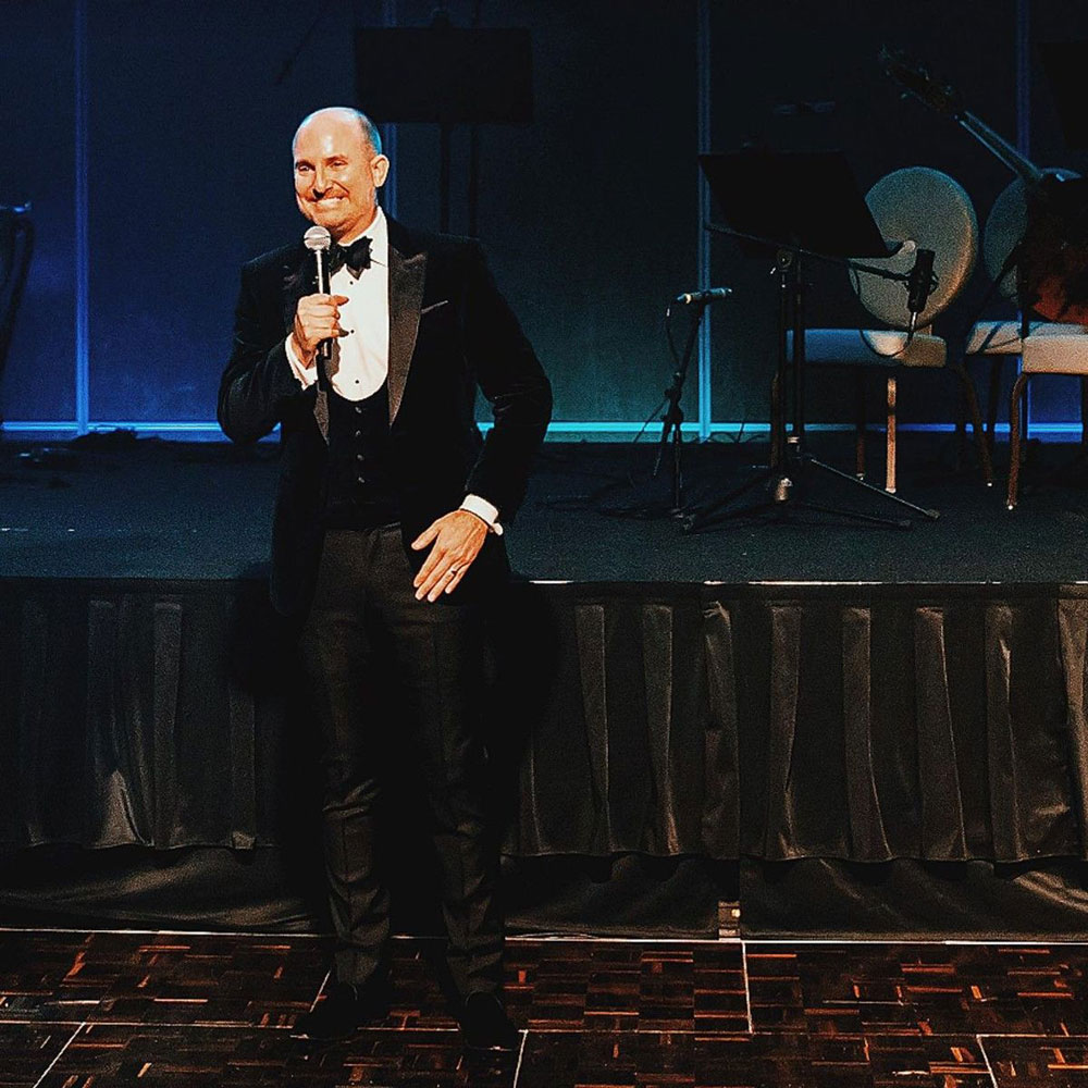 Close up of Brian Ritter on stage with a tuxedo on