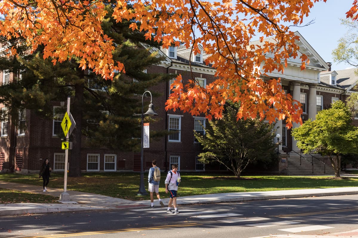 students crossing in front of Breidenbaugh Hall with orange maple leaves