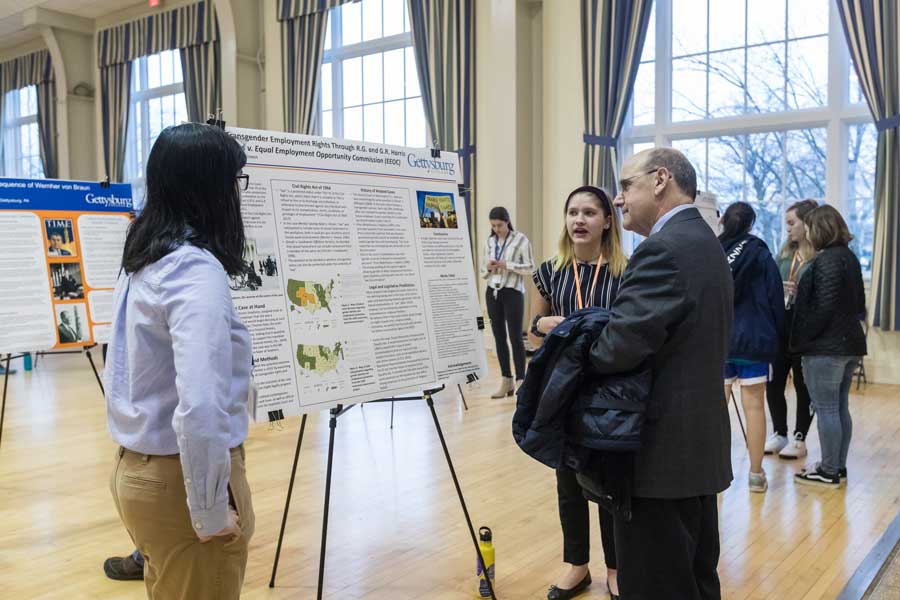 Bob Iuliano at a CAFE Symposium looking at a student poster