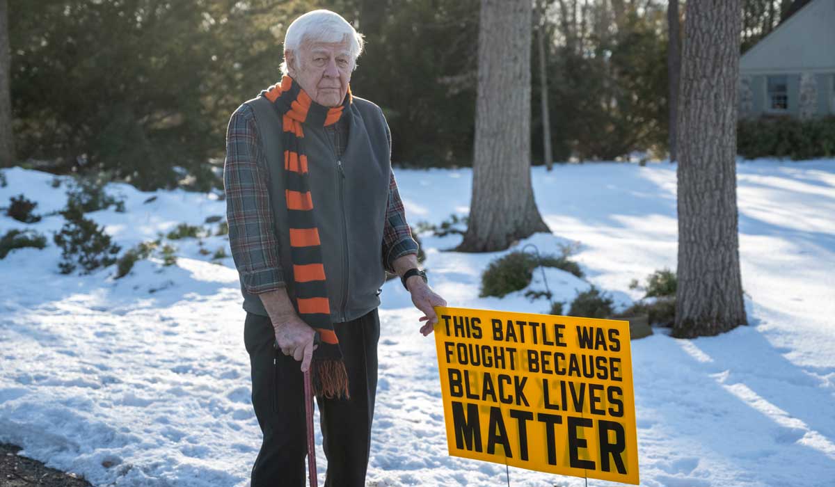 Karl Mattson stands in his front yard with a yard sign