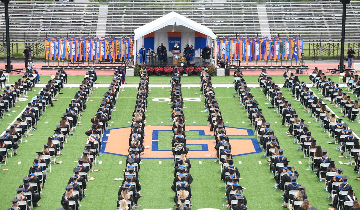 Graduates seated on the grass inside Musselman Stadium