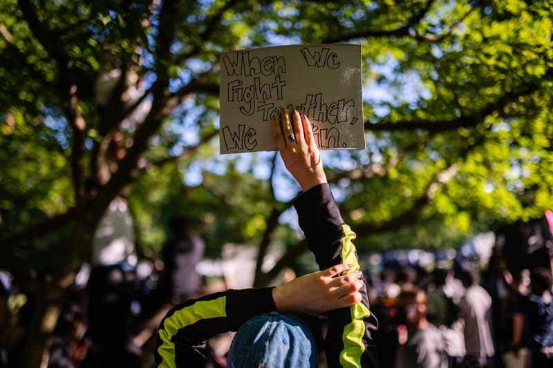 Protestor holding a sign that says When we fight together, we win