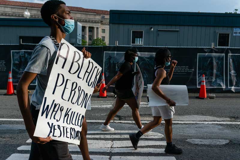 Man carrying a sign walking towards the White House