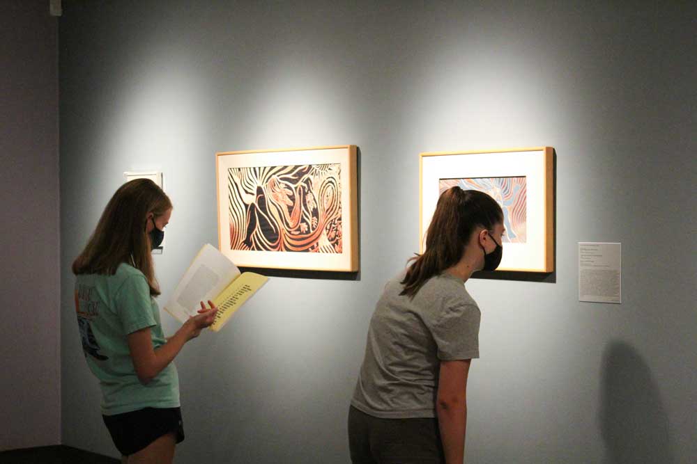 Two students viewing artwork in an art gallery with gray walls