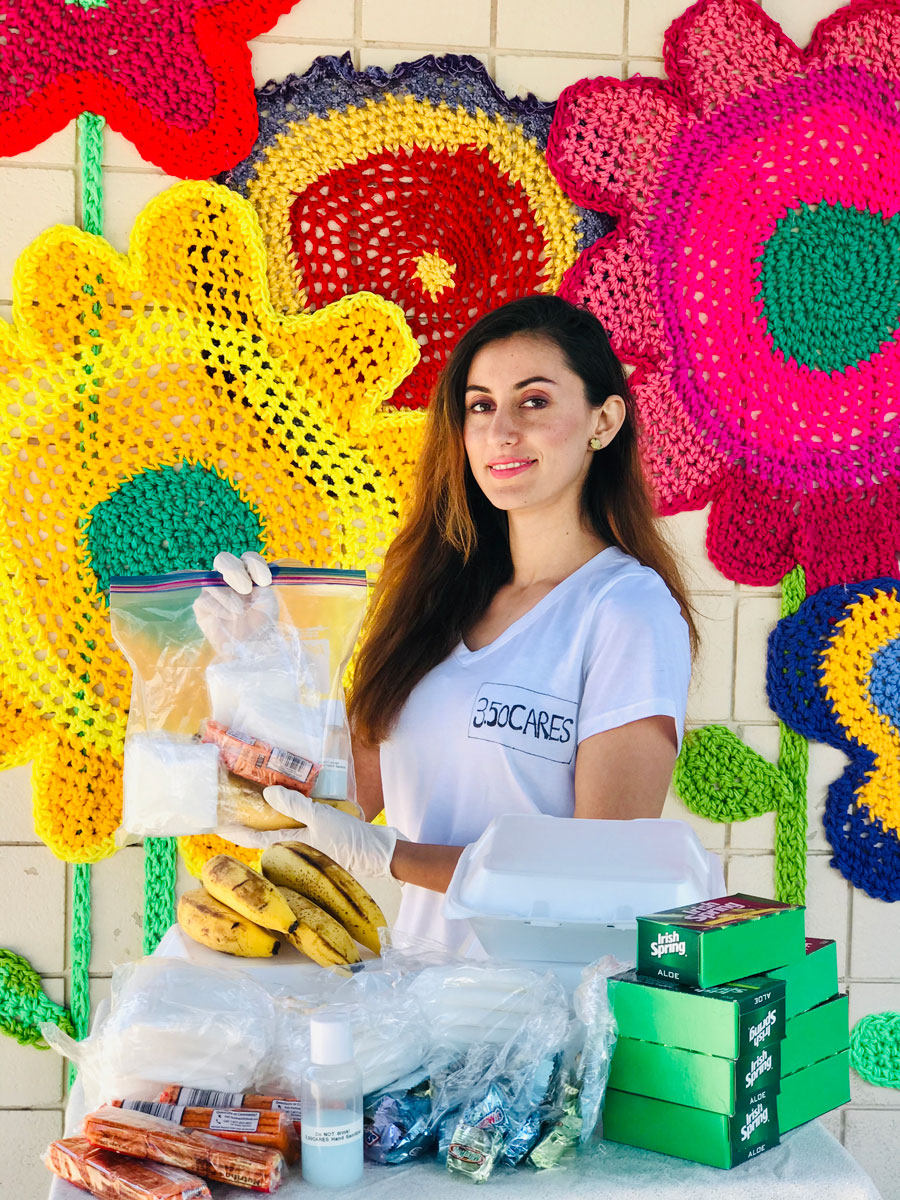 Hamasa Ebadi holding a donation bag with a table of donated products in front of her