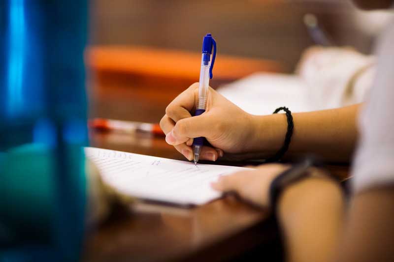 Student’s hand writing on a desk