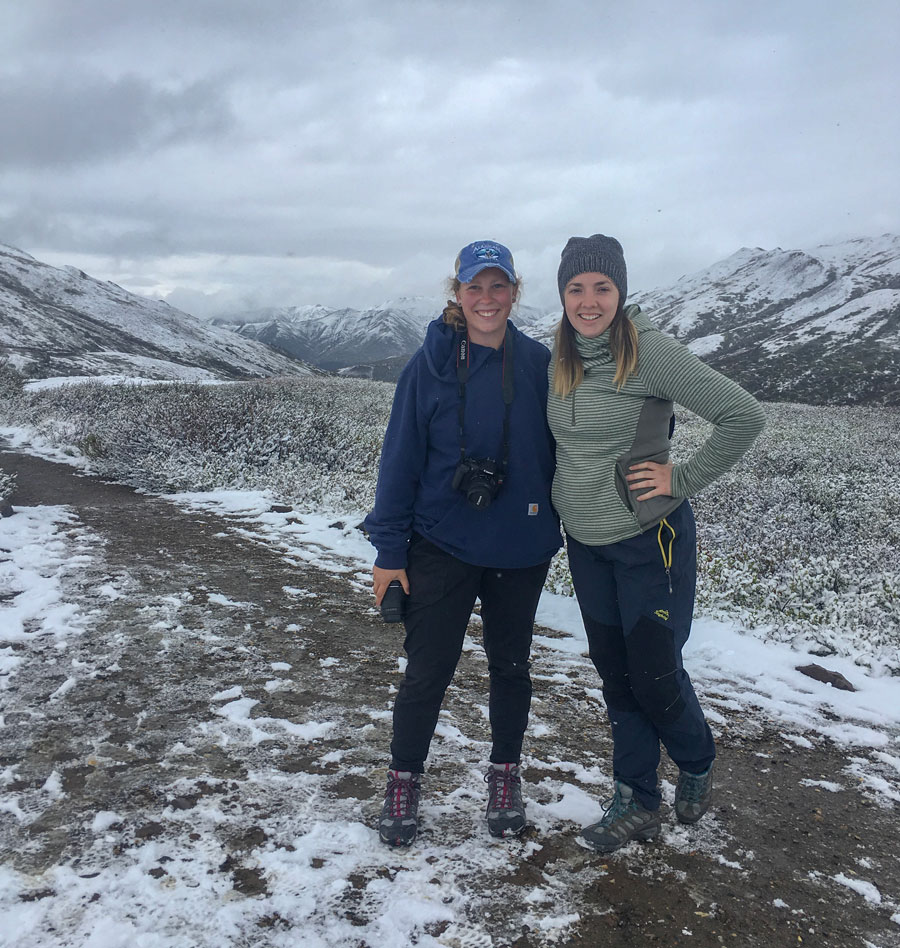 Hannah Collins and Sarah Scott Alley outside with snow covered mountains behind them