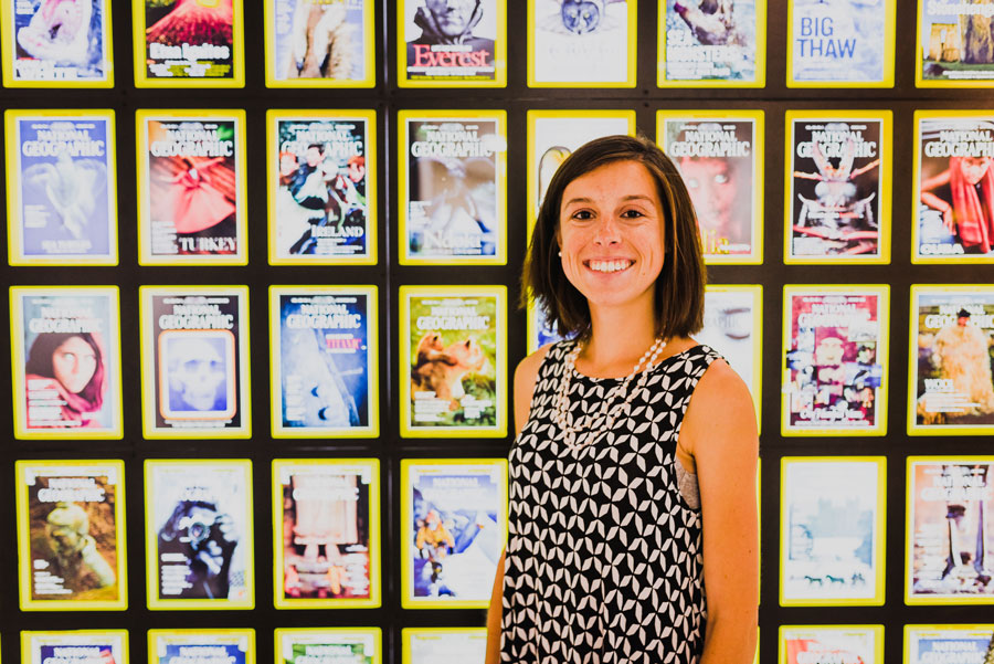 Elizabeth Hilfrank posing in front of an illumnated wall of National Geographic magazine covers