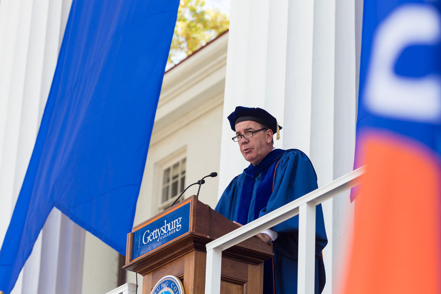 Installation ceremony with Chair of the Board David Brennan speaking from a podium in front of Penn Hall