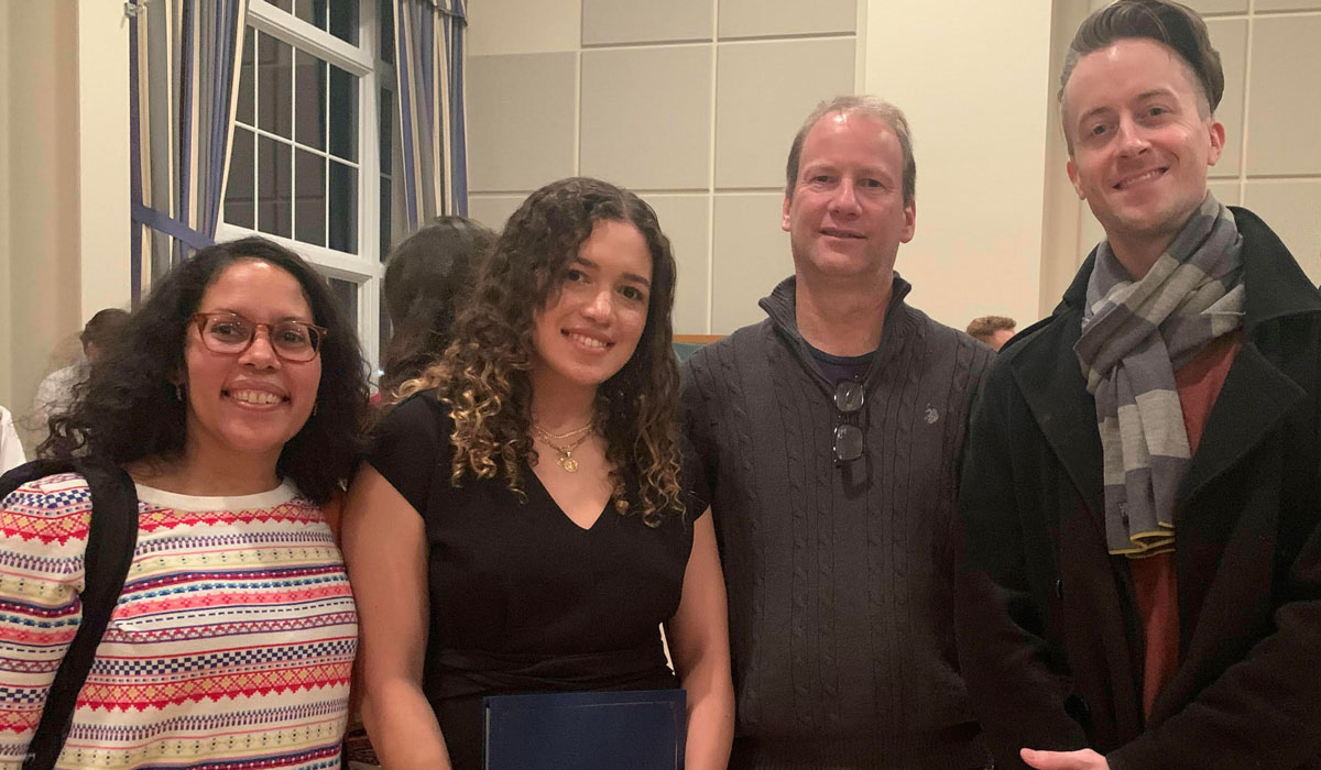 Flores posing with three of her professors at a graduation ceremony