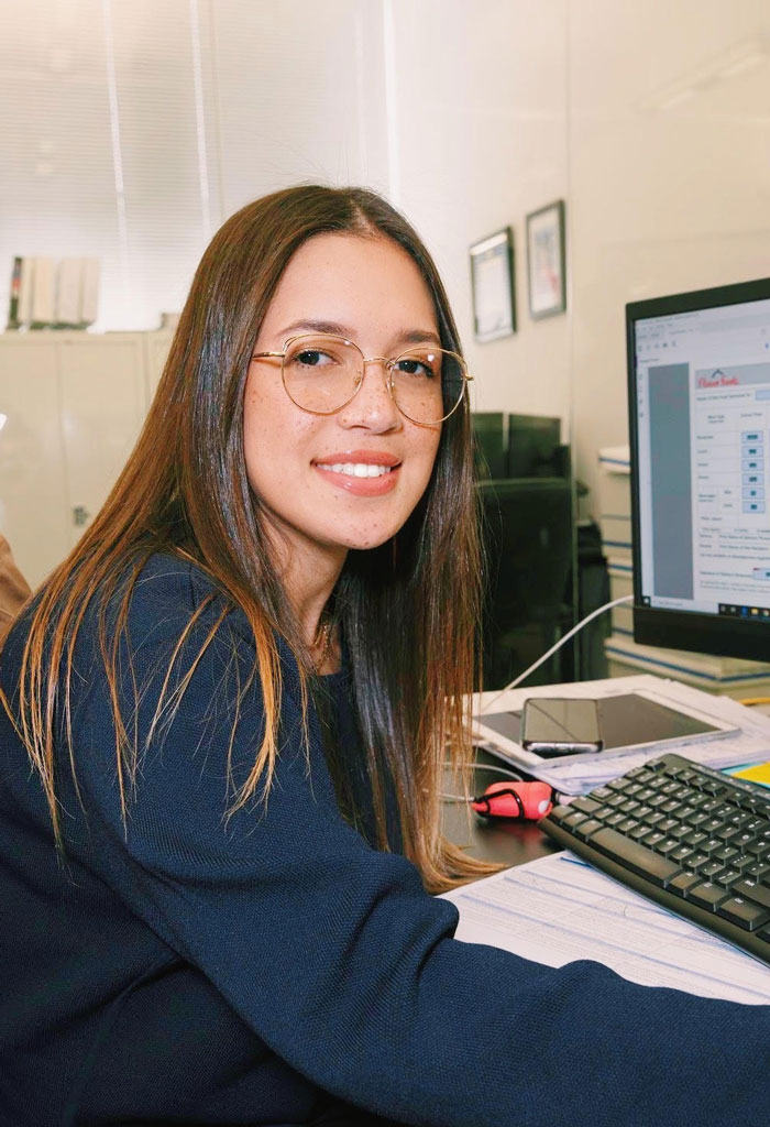 Flores sitting at a computer in an office