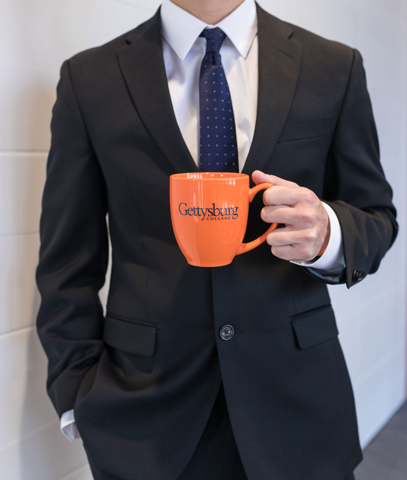 Kevin Benavente holding an orange Gettysburg College coffee mug