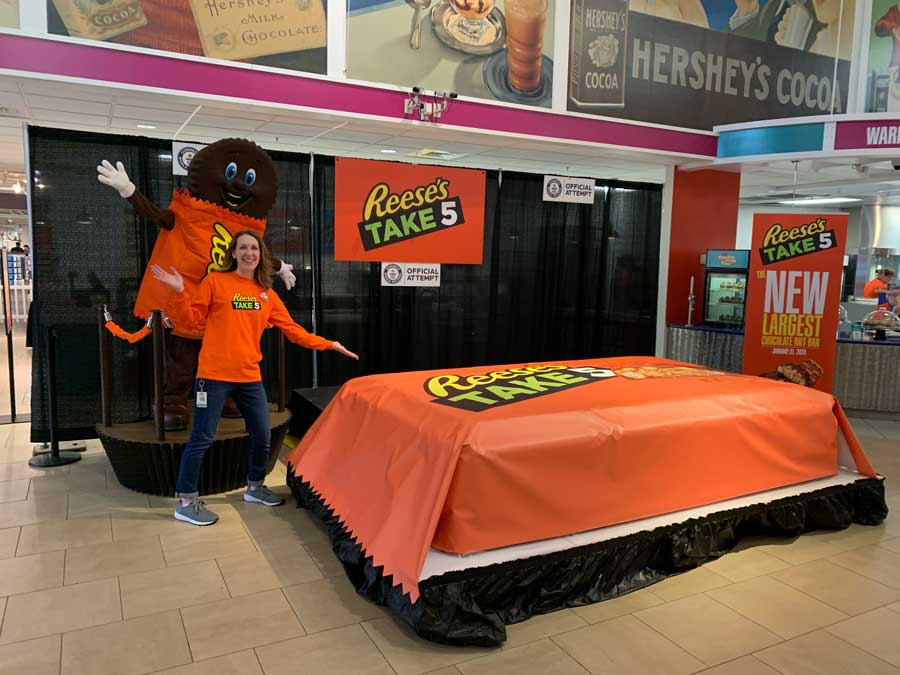 Kimberly McMenamin standing next to a large Reeses Take 5 chocolate bar