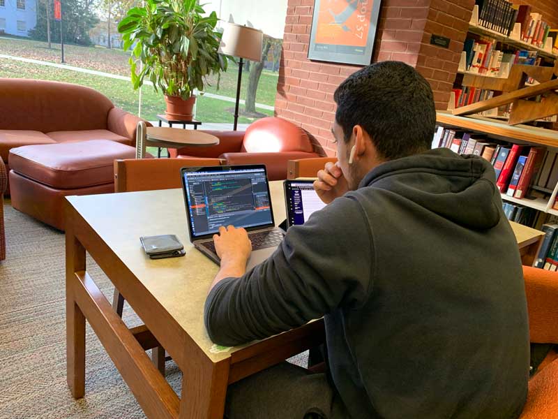 Male student using his laptop to study in the library