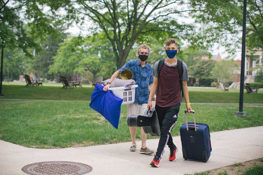 Student and parent carrying posessions across campus