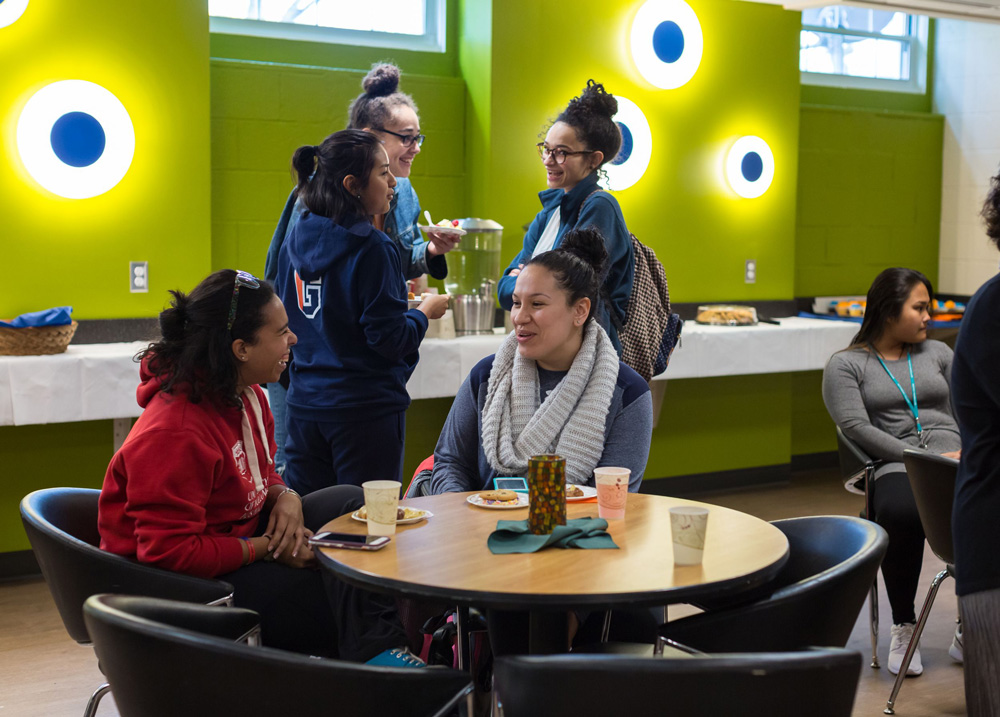 Students sitting around a table in a social space inside of the Office of Multicultural Engagement