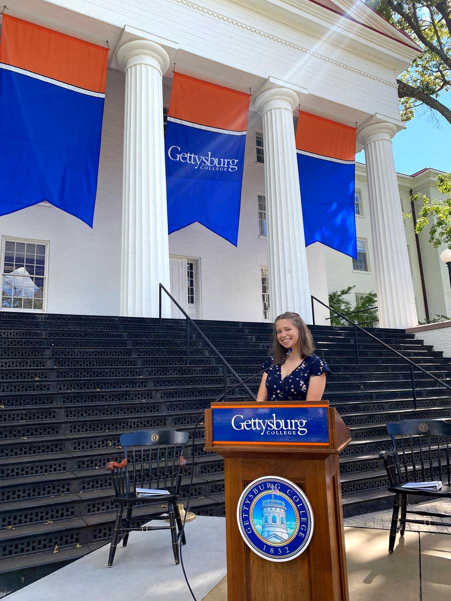 Pestretto standing at a podium in front of Penn Hall