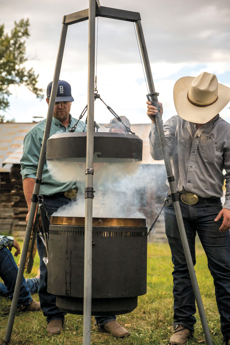 Roby and friends lifting the top off of the smoking firepit barrel