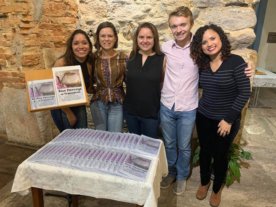 Anthony Wagner posing with other students with booklets on a table in front of them