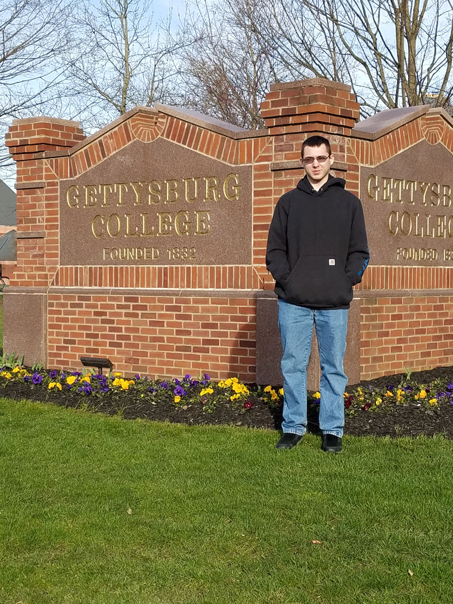 Steven Landry standing in front of the Gettysburg College entry sign
