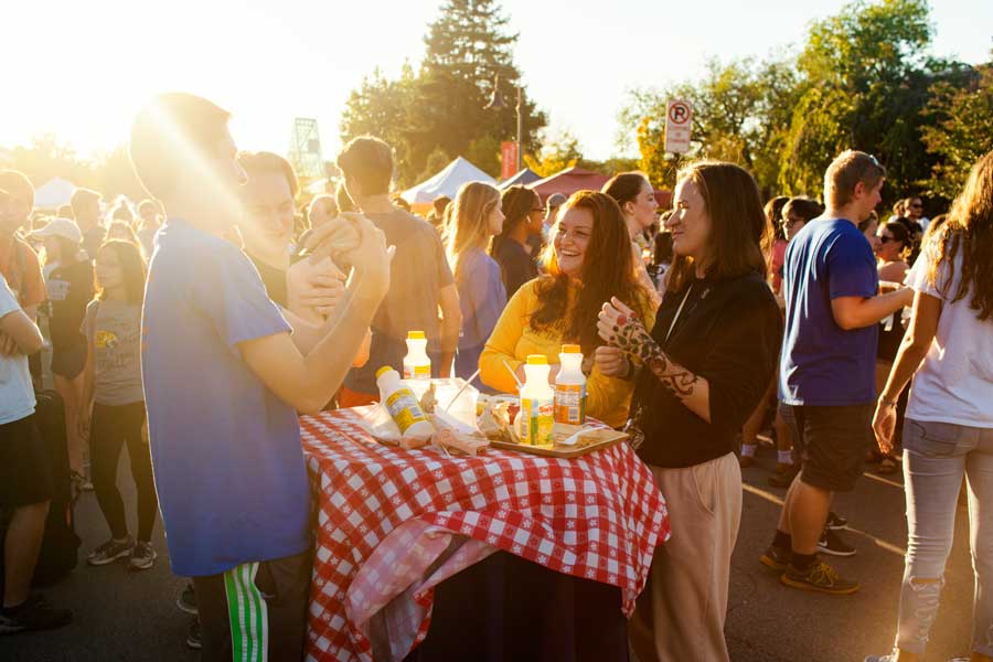 Students gathered around a table and eating food outdoors