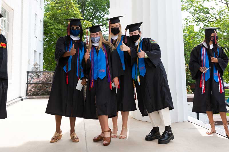 Students in their caps and gowns giving the camera a thumbs up