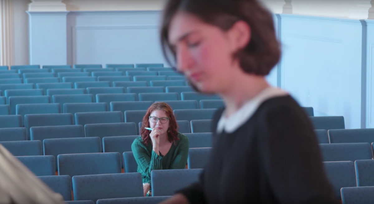 A student playing a piano in front of a faculty