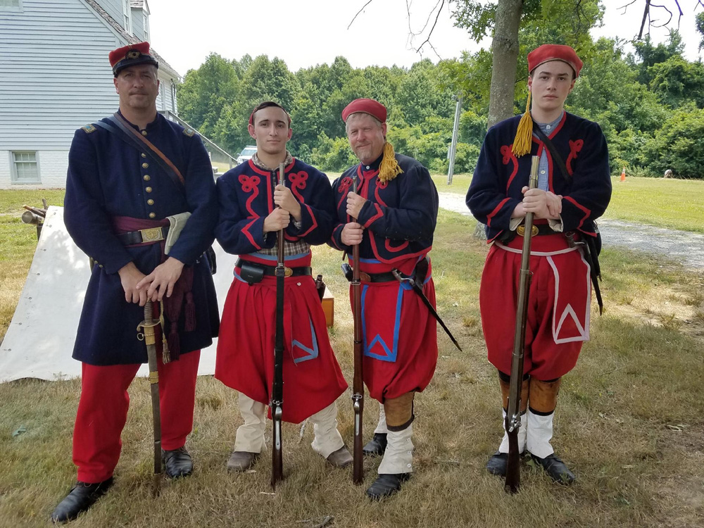Sean Thompson dressed in Civil War era attire with other reenactors
