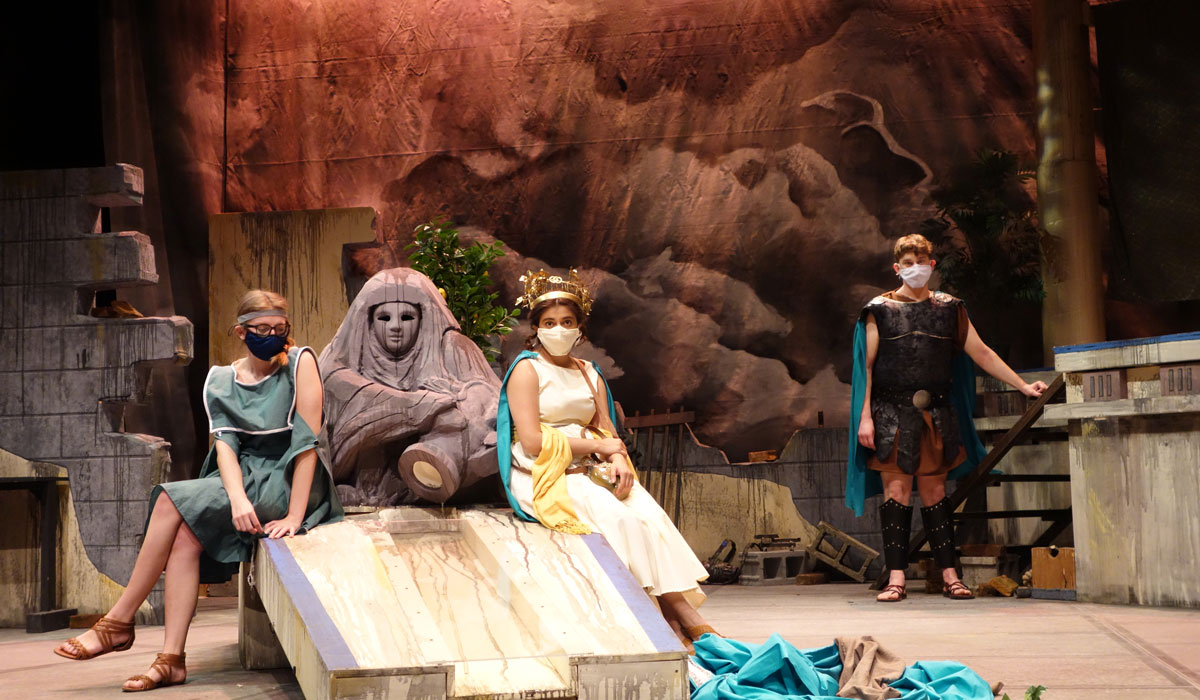 Actors and Actresses dressed in Roman attire and wearing masks on stage