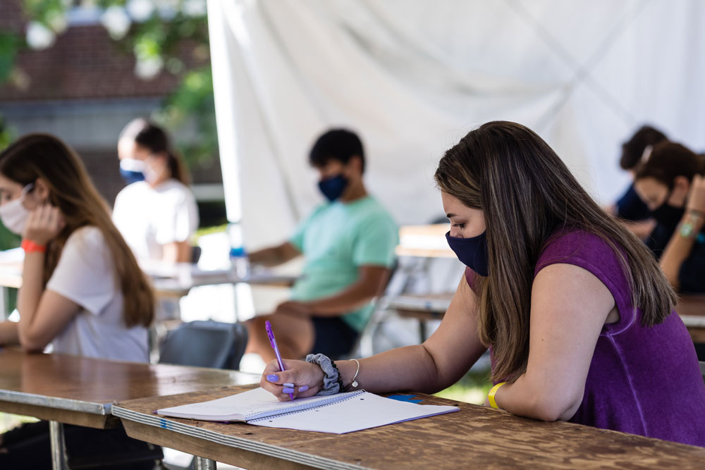 Student attending class in an outdoor tent while wearing a mask