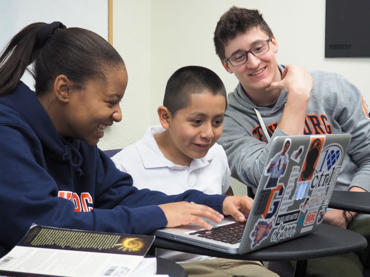 two CPS mentors looking at computer screen with young student