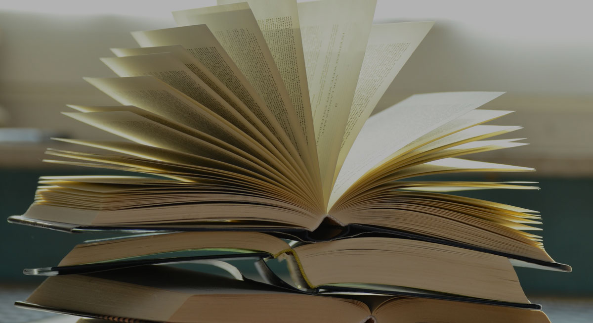 Photo of a pile of books with one book open on top of the pile