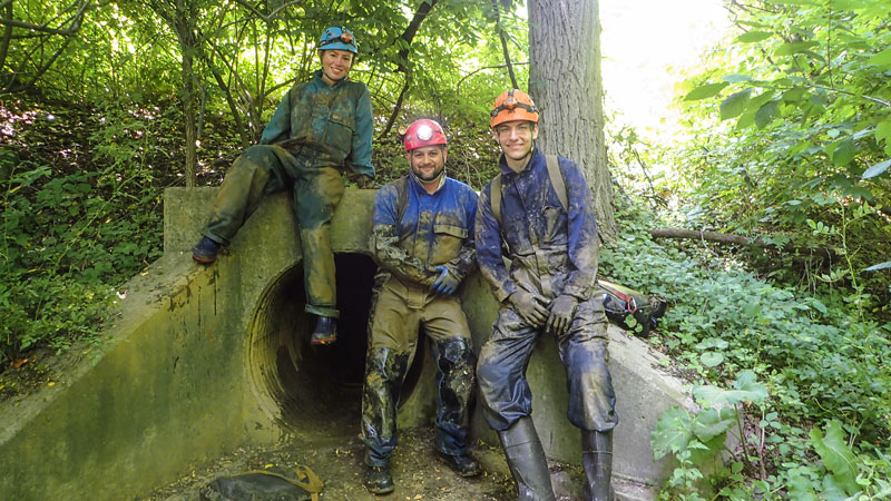 Students standing outside of the entrance to a cave