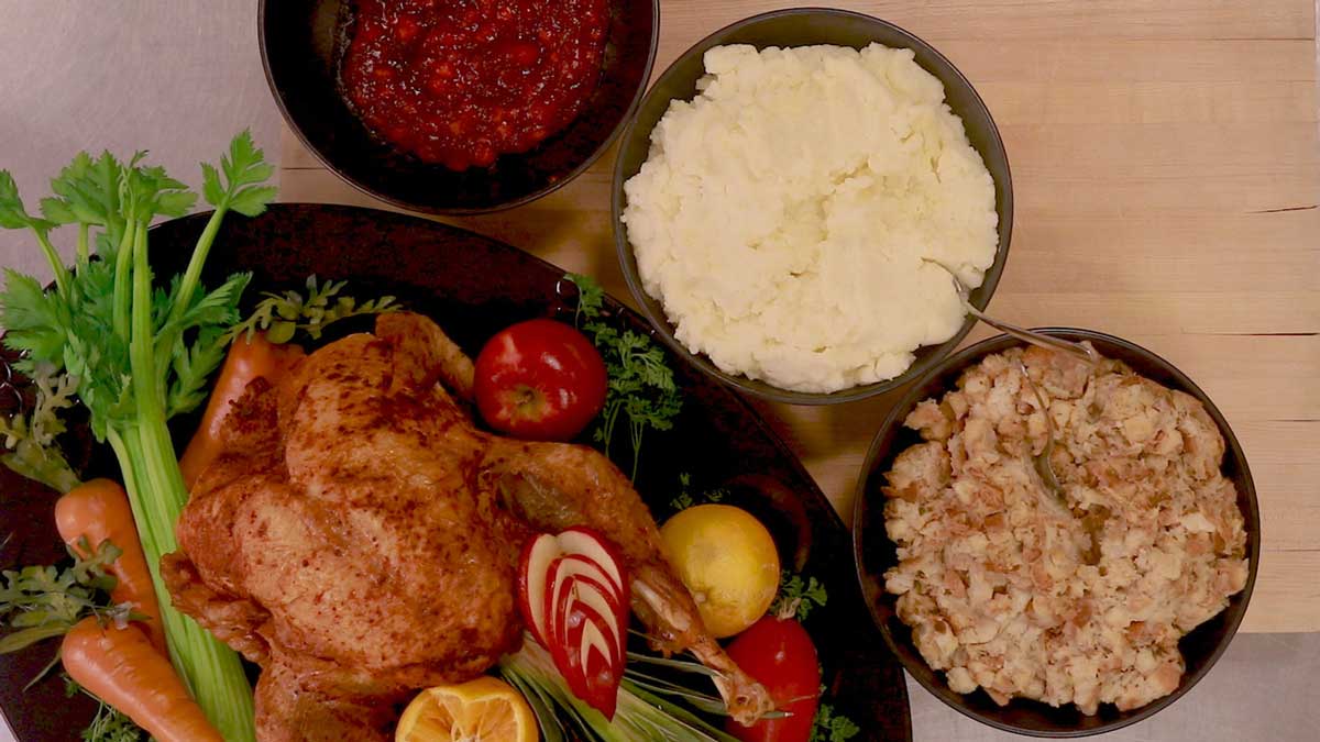 Roasted turkey, bowl of stuffing, mashed potatoes, and cranberry sauce from an overhead view