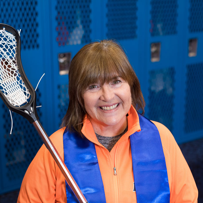 Coach Carole Cantele holding a field hockey stick