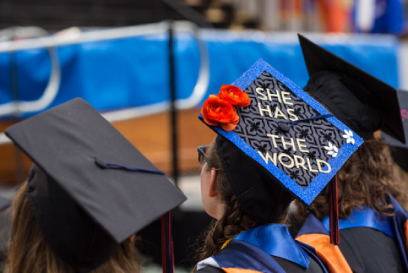 Photo of graduate with a cap that says She Has the World