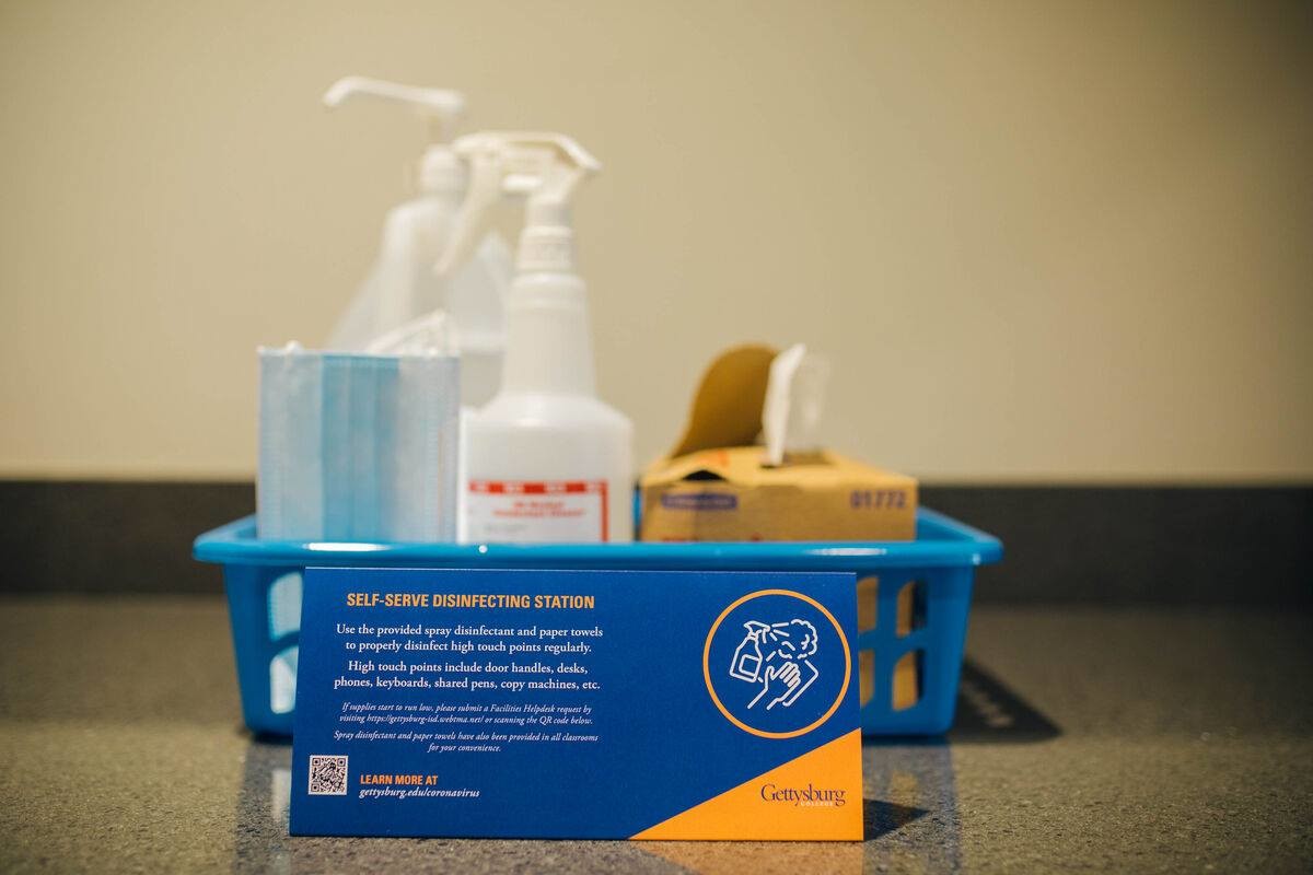 Cleaning supplies in a basket with a table tent that says self serve disenfecting station