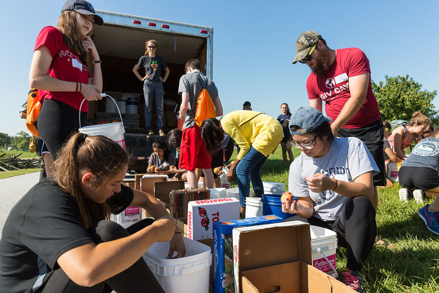 Students volunteering by packing produce into boxes during GIV Day