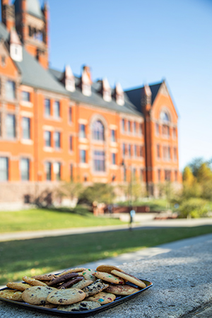 a platter of various cookies in front of a tall brick building with a bell tower