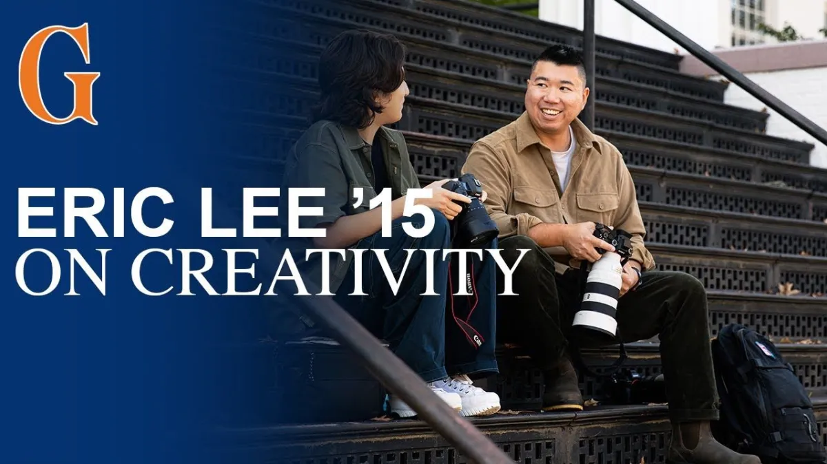 Eric Lee holding a camera while talking to a student
