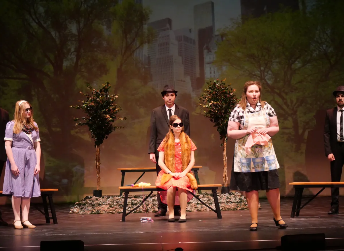 A theatrical scene shows several performers onstage