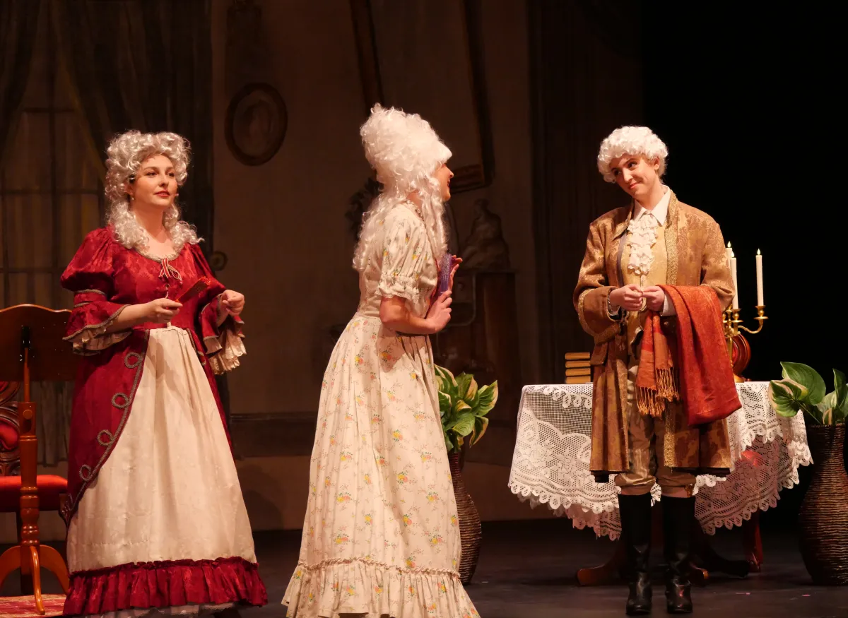 A theatrical scene shows performers onstage