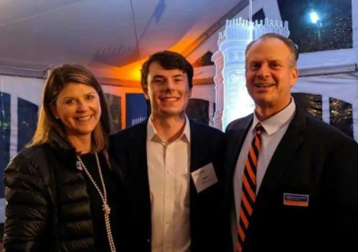 Three people posing together at an evening event
