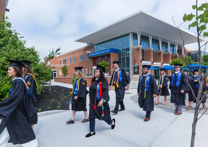 Graduates walk past the John F. Jaeger Center for Communications and Learning.