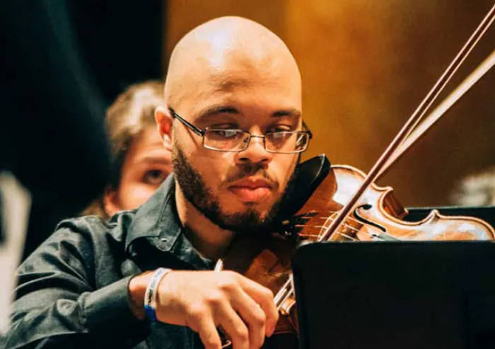 A student plays the violin at a concert.