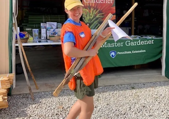 A student carrying gardening tools.