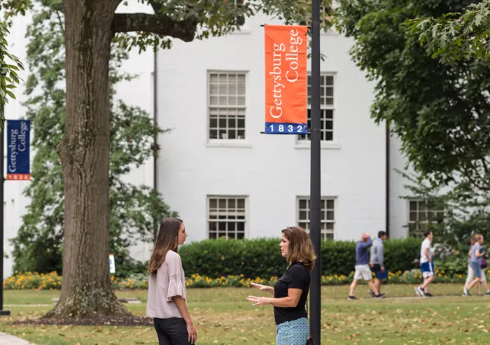 Two people talk outside a Gettysburg College building.