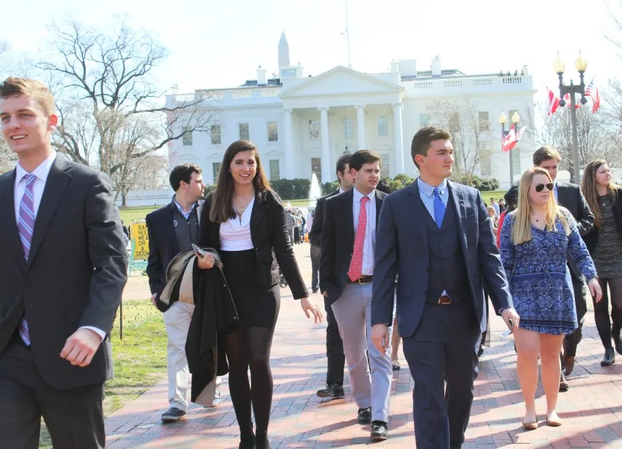 professionally dressed students walk  with White House in background