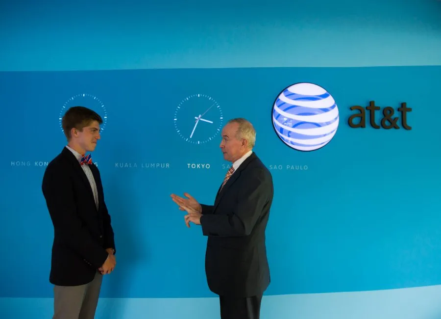 male student and alum speak together in front of blue wall with AT&T logo
